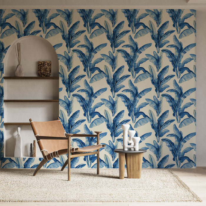 Un salon lumineux avec un papier peint tropical bleu représentant de grandes feuilles sur un fond clair, créant une atmosphère fraîche et apaisante.