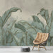 Une pièce moderne avec un papier peint tropical représentant de grandes feuilles stylisées dans des teintes vertes et dorées sur un fond doux et apaisant.