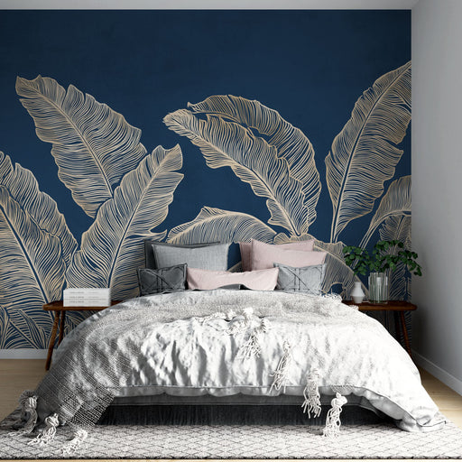 Une chambre moderne avec un papier peint tropical bleu nuit illustrant de grandes feuilles dorées, créant une ambiance élégante et apaisante.