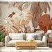 Un salon lumineux avec un papier peint tropical aux grandes feuilles dans des teintes beige et terracotta, créant une ambiance chaleureuse et naturelle.
