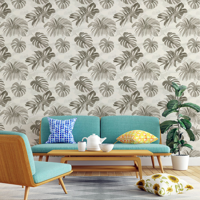 Un salon moderne avec un papier peint tropical aux motifs de feuilles de monstera dans des teintes de gris sur fond clair, créant une ambiance naturelle et apaisante.
