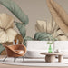 Un salon moderne avec un papier peint tropical aux grandes feuilles stylisées dans des tons doux de beige et vert, créant une ambiance chaleureuse et apaisante.