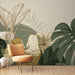 Une pièce moderne avec un papier peint tropical aux motifs de grandes feuilles exotiques dans des teintes vertes et dorées, créant une ambiance apaisante et naturelle.