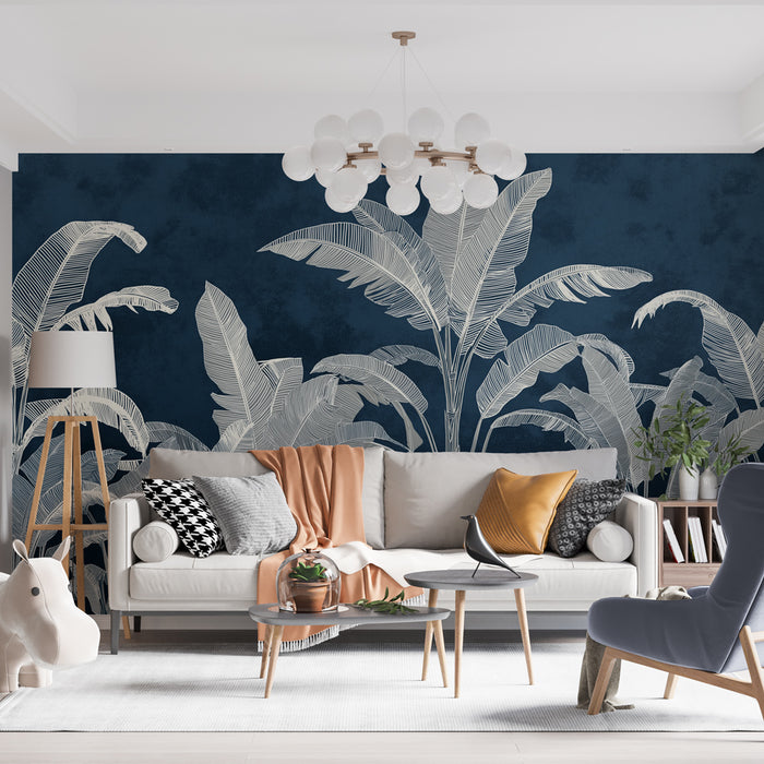 Un salon moderne avec un papier peint tropical bleu nuit illustrant de grandes feuilles blanches, créant une ambiance à la fois élégante et apaisante.