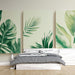 Une chambre moderne avec un papier peint tropical représentant de grandes feuilles vertes sur fond clair, créant une atmosphère apaisante et naturelle.