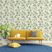Un salon lumineux avec un papier peint aux motifs de feuilles vertes sur fond crème, créant une atmosphère naturelle et apaisante.