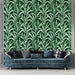 Un salon élégant avec un papier peint tropical vert foncé orné de grandes feuilles stylisées, créant une atmosphère vivante et apaisante.