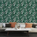 Un salon contemporain avec un papier peint tropical vert foncé orné de feuilles blanches et vertes, créant une atmosphère vivante et apaisante.