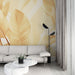 Un salon moderne avec un papier peint aux grandes feuilles dorées sur fond clair, créant une atmosphère chaleureuse et apaisante.