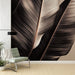 Un salon moderne avec un papier peint représentant de grandes feuilles stylisées dans des teintes de noir et beige, créant une atmosphère élégante et apaisante.