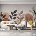 Un salon contemporain avec un papier peint aux motifs de feuilles stylisées dans des teintes douces de beige, terracotta et noir, créant une ambiance chaleureuse et apaisante.