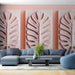 Un salon moderne avec un papier peint texturé représentant de grandes feuilles de monstera en relief sur un fond rose doux, créant une ambiance chaleureuse et naturelle.