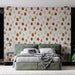 Une chambre moderne avec un papier peint aux motifs de feuilles stylisées dans des teintes chaudes de beige, orange et marron, créant une ambiance chaleureuse et accueillante.