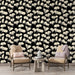 Un salon contemporain avec un papier peint floral noir et crème, présentant des motifs de feuilles délicates qui créent une ambiance élégante et apaisante.
