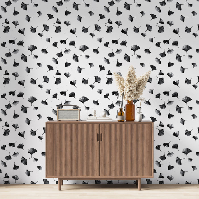 Une pièce moderne avec un papier peint noir et blanc illustrant des feuilles de ginkgo, créant une atmosphère élégante et artistique.