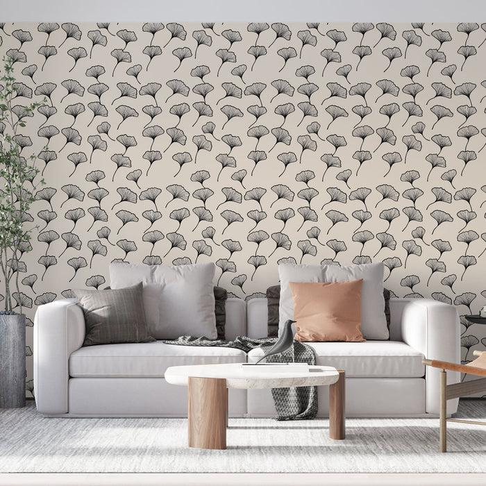 Un salon moderne avec un papier peint aux motifs de feuilles de ginkgo en noir sur fond crème, créant une ambiance élégante et apaisante.