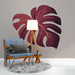 Une pièce moderne avec un papier peint représentant une grande feuille de monstera aux teintes bordeaux sur fond gris, créant une ambiance chaleureuse et accueillante.
