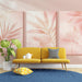 Un salon lumineux avec un papier peint aux motifs de feuilles tropicales dans des teintes douces de rose, créant une atmosphère apaisante et chaleureuse.