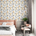 Une chambre moderne avec un papier peint floral aux motifs de feuilles et fleurs en noir et jaune sur fond clair, créant une ambiance chaleureuse et accueillante.