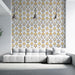 Un salon moderne avec un papier peint aux motifs de feuilles stylisées en or et noir sur fond blanc, créant une ambiance élégante et chaleureuse.