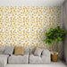 Un salon moderne avec un papier peint aux motifs de feuilles dorées sur fond blanc, créant une ambiance chaleureuse et naturelle.