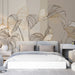Une chambre moderne avec un papier peint aux lignes dorées représentant de grandes feuilles stylisées sur un fond neutre, créant une ambiance élégante et apaisante.