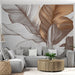 Un salon moderne avec un papier peint représentant de grandes feuilles stylisées dans des teintes de beige et marron, créant une atmosphère chaleureuse et apaisante.