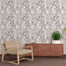 Une salle de séjour avec un papier peint aux motifs de feuilles délicates en nuances de gris, créant une atmosphère apaisante et élégante.