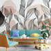 Un salon moderne avec un papier peint aux motifs de feuilles stylisées en noir sur un fond aux teintes douces de rose et beige, créant une ambiance apaisante et artistique.