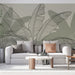 Un salon moderne avec un papier peint représentant de grandes feuilles tropicales en lignes noires sur un fond doux et apaisant, créant une atmosphère naturelle et élégante.
