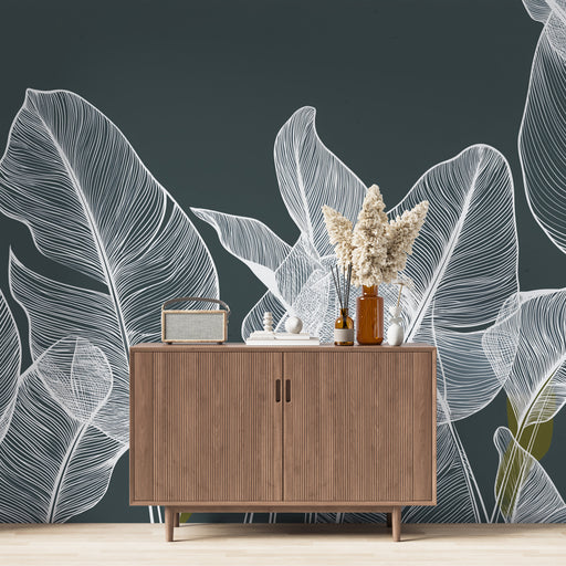 Une salle de séjour moderne avec un papier peint représentant de grandes feuilles blanches sur fond sombre, créant une ambiance élégante et apaisante.