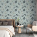 Une chambre élégante avec un papier peint aux motifs de feuilles délicates en noir et blanc sur fond bleu clair, créant une atmosphère apaisante et naturelle.