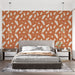 Une chambre moderne avec un papier peint terracotta orné de feuilles blanches, créant une ambiance chaleureuse et naturelle.