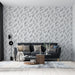 Un salon moderne avec un papier peint aux motifs de feuilles délicates en noir sur fond clair, créant une ambiance apaisante et naturelle.