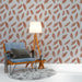 Une pièce de salon avec un papier peint aux motifs de plumes en terracotta sur fond clair, créant une ambiance chaleureuse et naturelle.