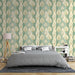 Une chambre apaisante avec un papier peint aux motifs de feuilles dorées sur fond vert et crème, créant une atmosphère naturelle et élégante.