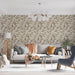 Un salon lumineux avec un papier peint aux motifs de feuilles dans des teintes beiges et brunes, créant une atmosphère chaleureuse et naturelle.