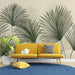 Un salon moderne avec un papier peint tropical représentant de grandes feuilles de palmier vertes sur fond beige, créant une atmosphère fraîche et accueillante.