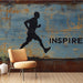 Une salle de sport avec un papier peint au style urbain représentant un coureur en silhouette noire sur fond bleu vieilli, créant une ambiance dynamique et inspirante.
