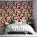 Une chambre moderne avec un papier peint coloré aux motifs floraux dynamiques, mêlant des teintes vives de rose, jaune et bleu marine, créant une ambiance joyeuse et énergisante.