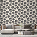 Un salon moderne avec un papier peint floral noir sur fond crème, créant une ambiance élégante et artistique.