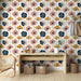 Une pièce lumineuse avec un papier peint floral aux motifs colorés de fleurs roses, jaunes et bleues sur fond clair, créant une atmosphère joyeuse et accueillante.