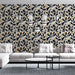 Un salon contemporain avec un papier peint floral noir et doré sur fond clair, créant une atmosphère élégante et chaleureuse.