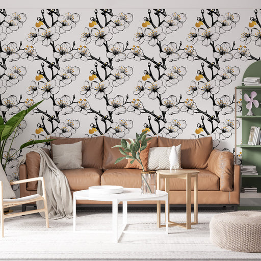 Un salon élégant avec un papier peint floral représentant des branches noires ornées de fleurs blanches et de touches jaunes, créant une atmosphère douce et accueillante.