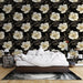 Une chambre élégante avec un papier peint floral aux grandes fleurs blanches et dorées sur fond noir, créant une atmosphère sophistiquée et chaleureuse.