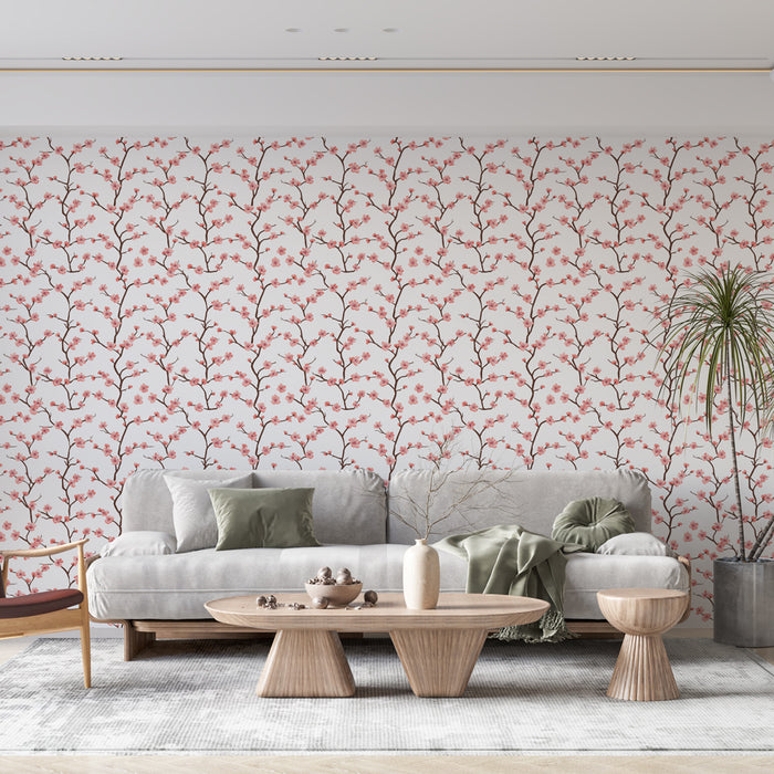 Un salon moderne avec un papier peint floral aux motifs de branches et fleurs roses sur fond blanc, créant une ambiance douce et accueillante.
