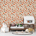 Une chambre d'enfant avec un papier peint floral aux teintes chaudes de rouge, beige et marron, créant une ambiance joyeuse et accueillante.