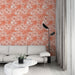 Un salon lumineux avec un papier peint floral aux teintes corail et beige, créant une atmosphère douce et accueillante.