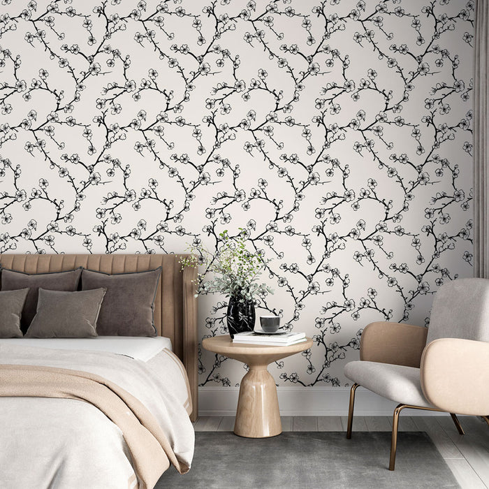 Une chambre élégante avec un papier peint floral noir et blanc représentant des branches délicates, créant une atmosphère apaisante et raffinée.