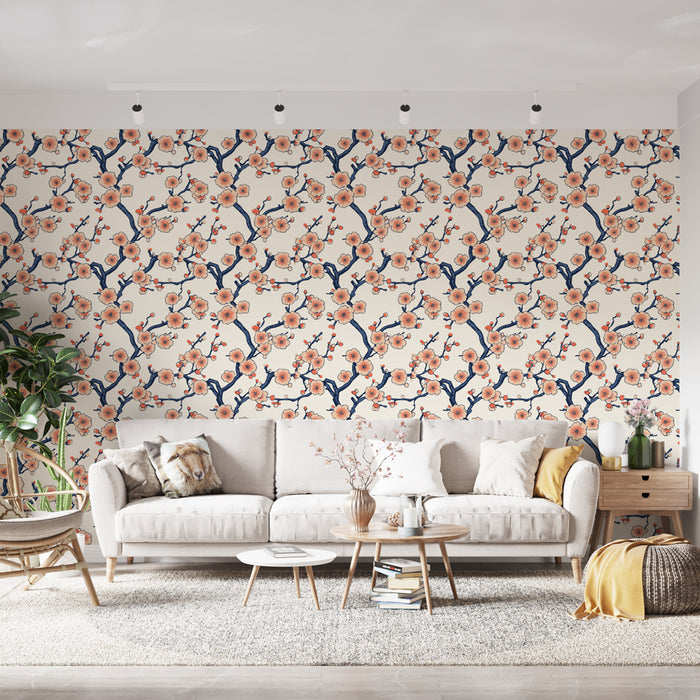 Un salon lumineux avec un papier peint floral aux motifs de branches et de fleurs roses sur fond crème, créant une ambiance douce et accueillante.